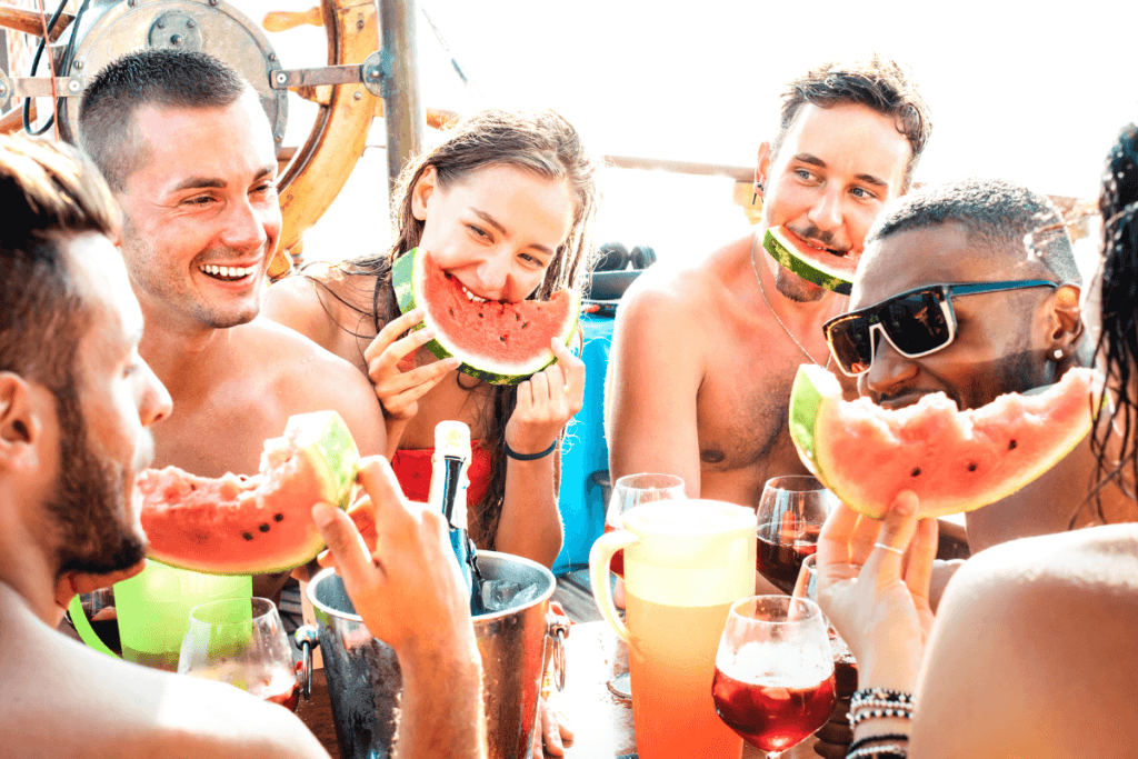 people on a boat party drinking and eating melon